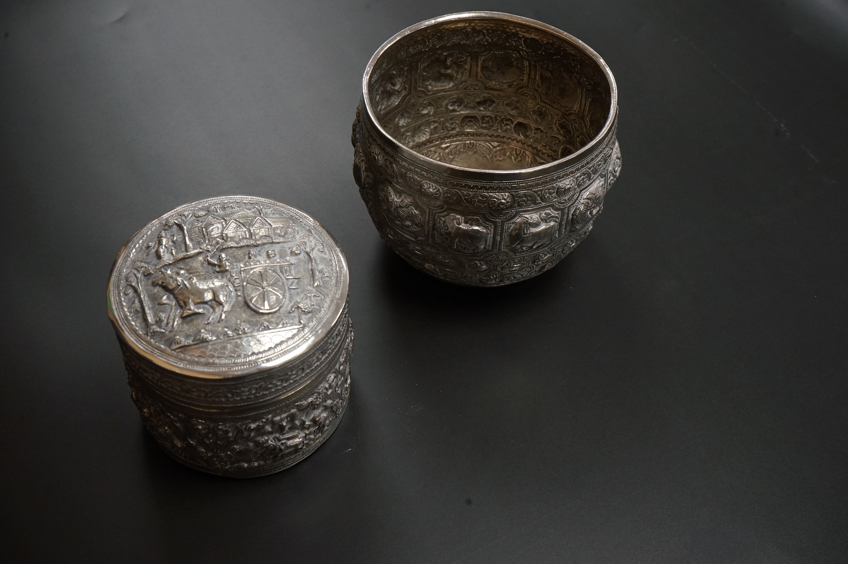 A Burmese embossed white metal circular bowl, signature to the base, diameter 11.4cm, together with a similar circular box and cover, 17oz.